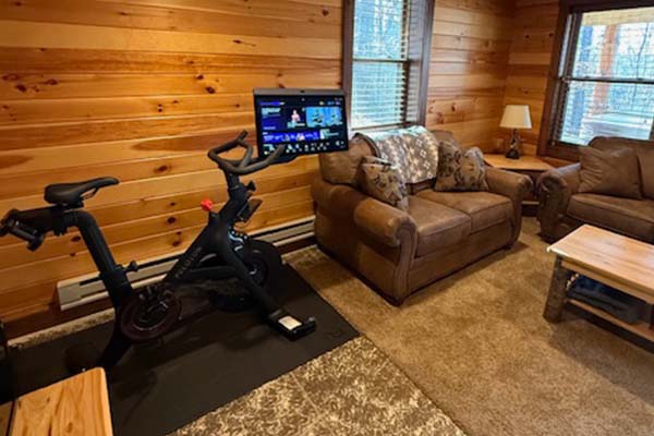 Peloton exercise bike with its touchscreen display against the knotty pine wall of the lower level
