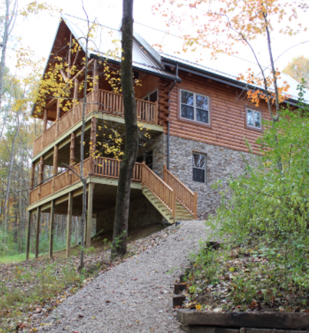 side view of log cabin view of covered porch overlooking woods